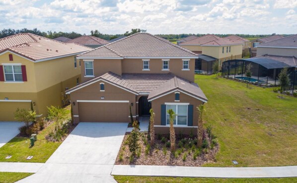 A residential building with a central garage, a covered patio, and a well-maintained lawn. - Amazing 6bds Single Home With Private Pool St7040 (Davenport)