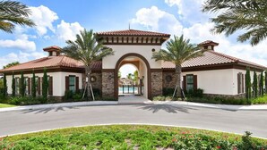 A two-story building with a central archway, surrounded by palm trees and a landscaped garden. - Amazing 6bds Single Home With Private Pool St7040 (Davenport)