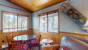 Une pièce avec une table en verre, des chaises en bois, un canapé en cuir et un plafond en bois.