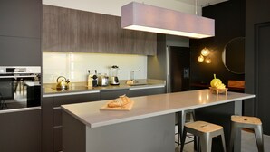 Une cuisine moderne dotée d’un îlot central, d’appareils électroménagers en acier inoxydable et d’un luminaire suspendu.