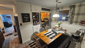 A cozy kitchen with a wooden table, chairs, and a hanging light fixture.