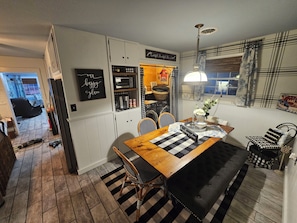 A cozy kitchen with a wooden table, chairs, and a hanging light fixture.