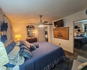 A bedroom with a bed, a ceiling fan, a mirror, a dresser, and a framed quote on the wall.