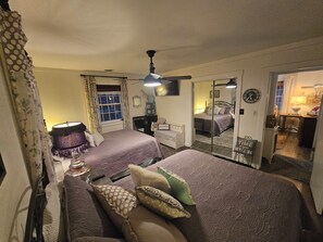 A bedroom with two beds, a sofa, a mirror, and a window with curtains.