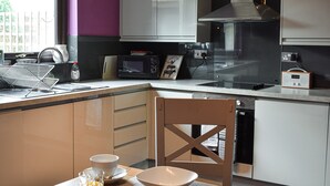A modern kitchen with a microwave, stove, and sink. There is a dining table with a bowl and a glass of orange juice. - 2 bedroom accommodation in Horton-in-Ribblesdale, near Settle (Horton-in-Ribblesdale, near Settle)