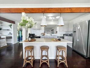 A modern kitchen with a central island, stainless steel appliances, and hanging pendant lights.