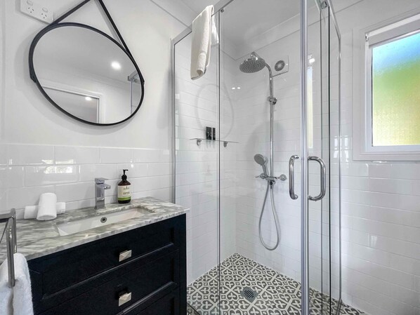 A modern bathroom with a glass-enclosed shower, a marble sink, and a black vanity.