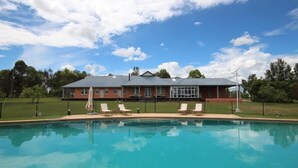 Une piscine avec des chaises longues et un bâtiment avec un toit rouge et des fenêtres en arrière-plan.
