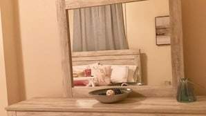 A wooden dresser with a mirror, a bowl, and a vase on top.