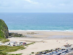 A coastal view with a beach, parking area, and buildings. - Prince Croft Cottage - UK12560 (Mount Hawke, near Redruth)