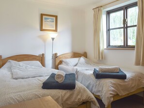 A room with two wooden beds, a floor lamp, a window with curtains, and a framed picture on the wall. - Prince Croft Cottage - UK12560 (Mount Hawke, near Redruth)