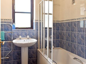 A bathroom with a white sink, a glass-enclosed shower, and blue-tiled walls. - Prince Croft Cottage - UK12560 (Mount Hawke, near Redruth)