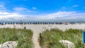 A beach with rows of umbrellas and beachgoers.