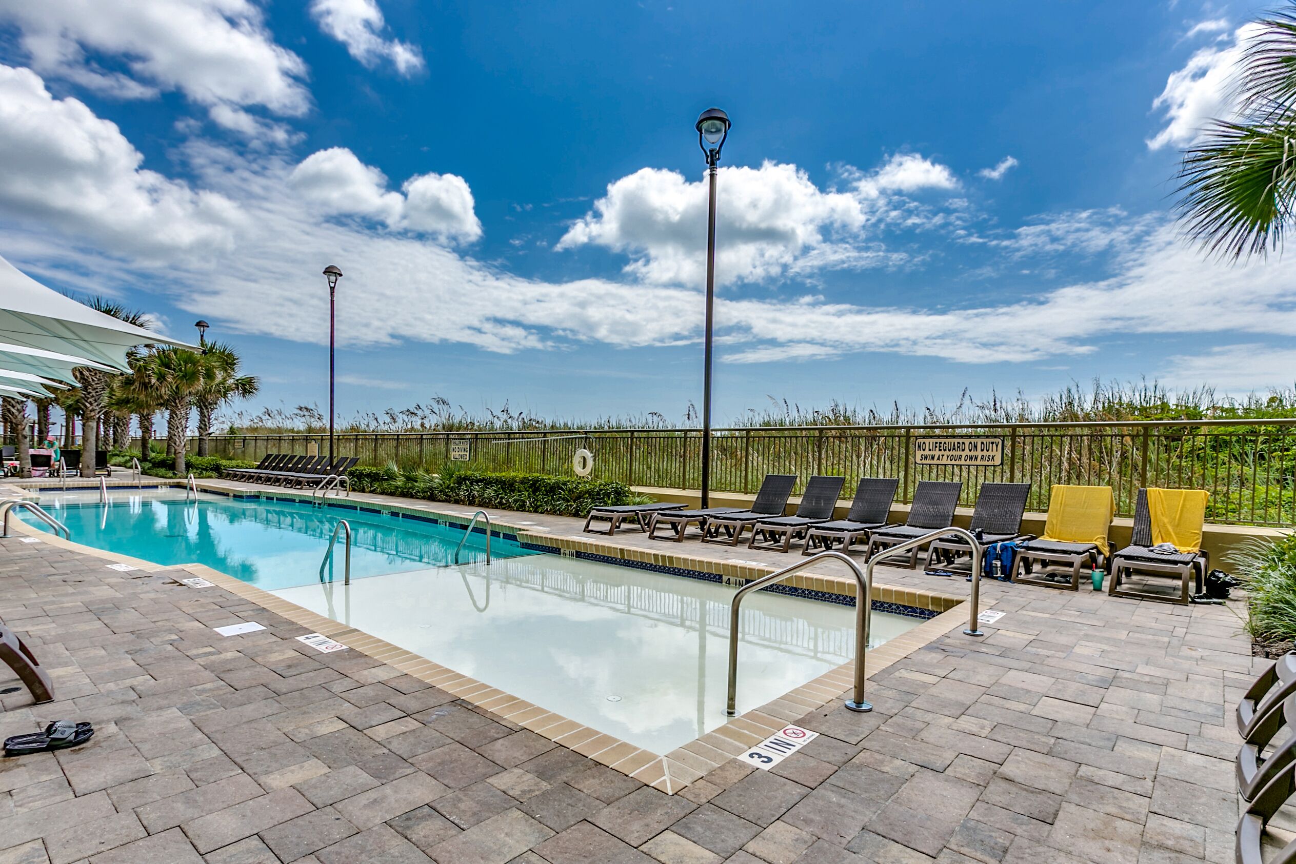 A swimming pool with lounge chairs and a lifeguard stand.