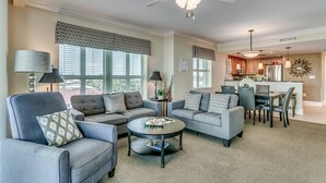 A modern living room with grey sofas, a coffee table, and a dining area with chairs and a table.