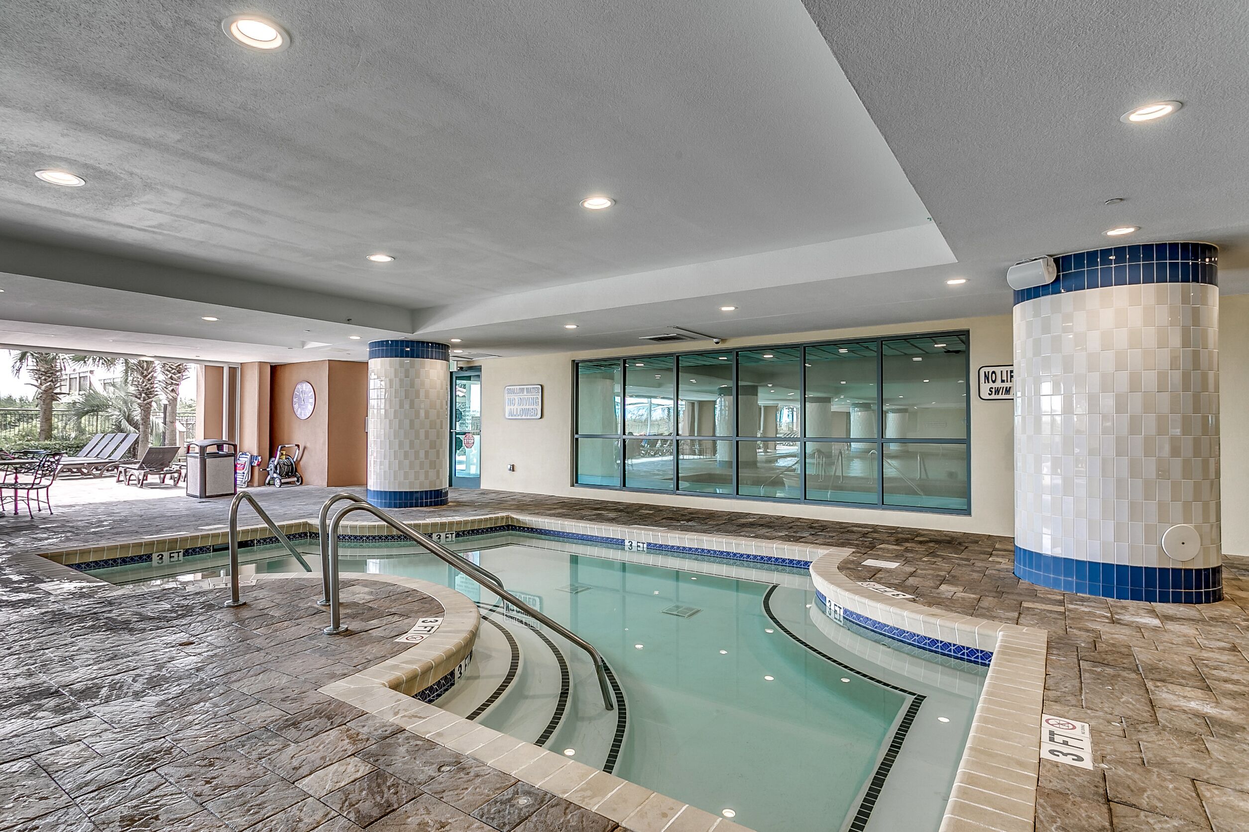 Una piscina interior con agua cristalina, paredes de azulejos y tragaluces.