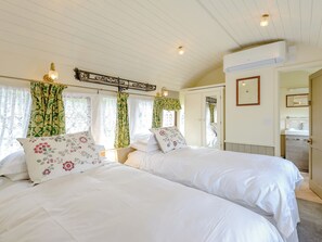 A bedroom with two beds, a wardrobe, a mirror, and an air conditioning unit. - A truly beautiful train conversion, a stone’s throw from the River Test. (Horsebridge)