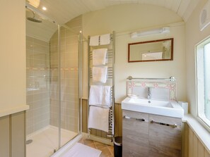 A bathroom with a glass shower enclosure, a sink with a mirror, and a towel rack. - A truly beautiful train conversion, a stone’s throw from the River Test. (Horsebridge)