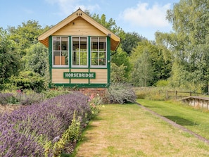 Un edificio con un cartel que dice 'HORSEBRIDGE', rodeado de abundante vegetación y un campo de lavanda.