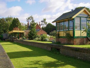 A traditional building with a sign reading 'HORSEBRIDGE,' a brick wall, and a grassy area. - A truly beautiful train conversion, a stone’s throw from the River Test. (Horsebridge)
