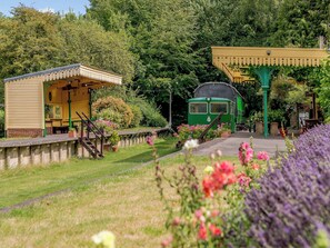 A green train, a yellow building, and a covered area with steps. - A truly beautiful train conversion, a stone’s throw from the River Test. (Horsebridge)