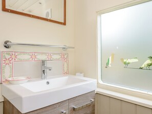 A bathroom with a white sink, a mirror, a towel rack, and a window with a view of birds. - A truly beautiful train conversion, a stone’s throw from the River Test. (Horsebridge)