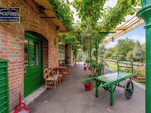 A brick building with a green door, outdoor seating, and a sign for Pickfords Parcel Express. - A truly beautiful train conversion, a stone’s throw from the River Test. (Horsebridge)