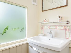 A bathroom with a window, a sink, a mirror, and a shelf with decorative items. - A truly beautiful train conversion, a stone’s throw from the River Test. (Horsebridge)