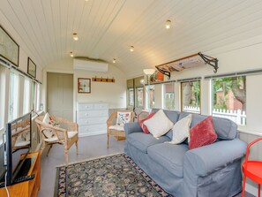 A living room with a grey sofa, wicker chairs, a white dresser, and a TV. - A truly beautiful train conversion, a stone’s throw from the River Test. (Horsebridge)