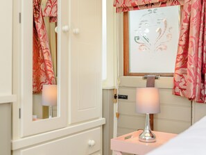 A bathroom with a mirror, a sink, a towel rack, and a window with curtains.