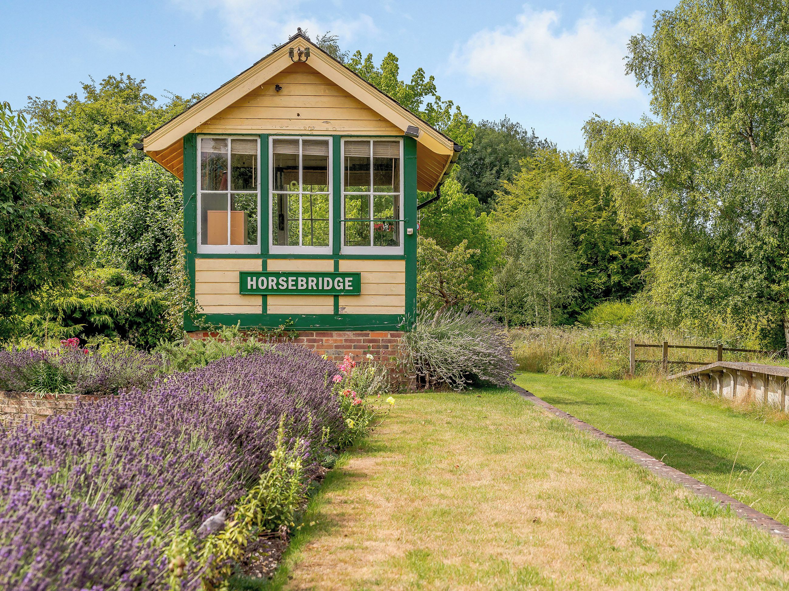 A building with a sign reading 'HORSEBRIDGE' surrounded by lush greenery and a lavender field.