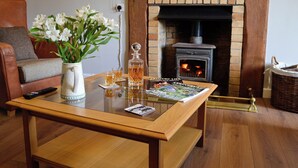Una sala de estar acogedora con chimenea, una mesa de centro con una revista, un jarrón con flores y un sillón de cuero.