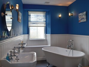 Un baño con una bañera independiente, un lavamanos y una ventana con vistas al exterior.