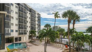 A hotel with a pool, palm trees, and a view of the beach. - Fort Myers Beach front Condo with amazing view of Gulf (Fort Myers Beach)