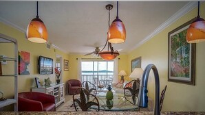 A kitchen with granite countertops, a red leather chair, a glass-top dining table, and pendant lights. - Fort Myers Beach front Condo with amazing view of Gulf (Fort Myers Beach)