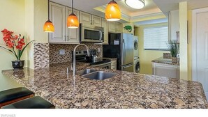 A kitchen with granite countertops, stainless steel appliances, and pendant lighting. - Fort Myers Beach front Condo with amazing view of Gulf (Fort Myers Beach)