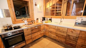 A modern kitchen with wooden cabinets, a built-in oven, and a large window. - Spacieux Chalet, proche des Télésièges,  Terrasse (Valloire)