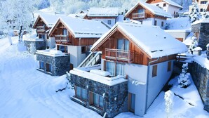 A snow-covered lodge with multiple wooden cabins, stone foundations, and balconies. - Spacieux Chalet, proche des Télésièges,  Terrasse (Valloire)