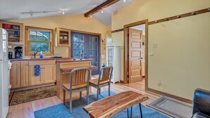 A kitchen with wooden cabinets, a dining table, and chairs. - Cute & Colourful Oceanside Cottage w Garden (Stinson Beach)