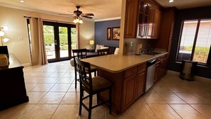 A kitchen with a central island, wooden cabinets, a ceiling fan, and a dining area with chairs. - EPIC Escape/Pool Access Near Malls Airport Hospita (Miami)