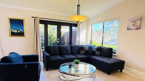 A living room with a sofa set, a glass coffee table, and a door leading outside. - EPIC Escape/Pool Access Near Malls Airport Hospita (Miami)