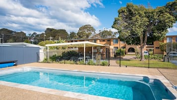 Relax by the pool surrounded by lush gardens and a scenic view.