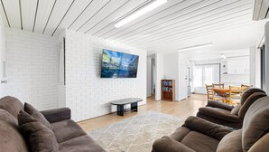 Ein modernes Wohnzimmer mit einer weißen Ziegelwand, einem Flachbildfernseher, einem Couchtisch und braunen Sofas.