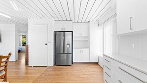 Eine moderne Küche mit weißen Schränken, einem Edelstahlkühlschrank und Holzböden.