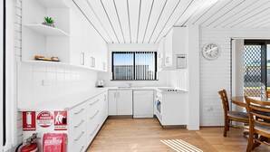 Eine moderne Küche mit weißen Schränken, Holzboden und einem Essbereich mit Holztisch und -stühlen.