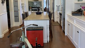 A spacious kitchen with a central island, white cabinetry, and a red accent piece.
