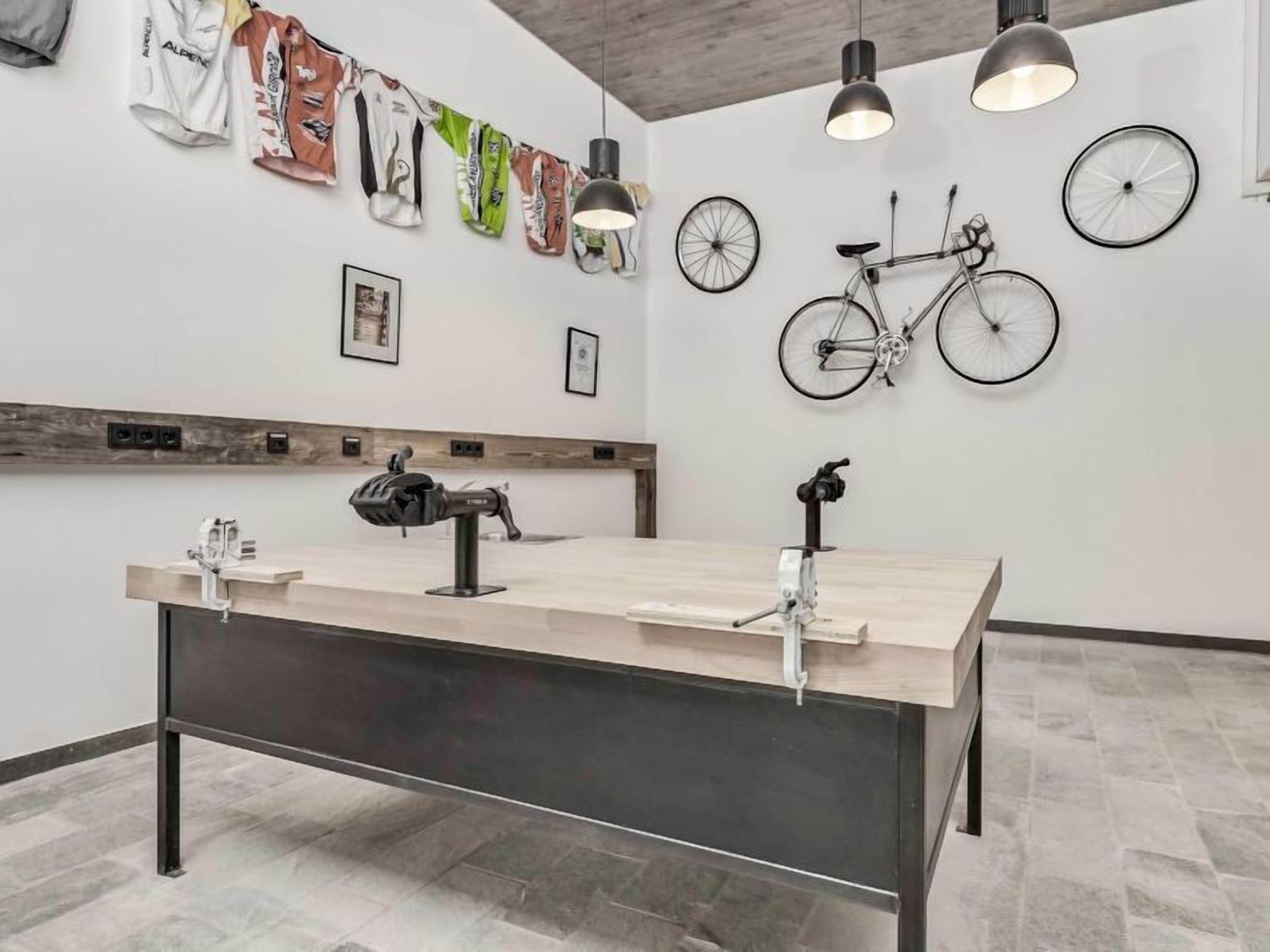 A reception area with a long reception desk, mounted bicycles, and a wall adorned with various items including a bicycle wheel and framed pictures.
