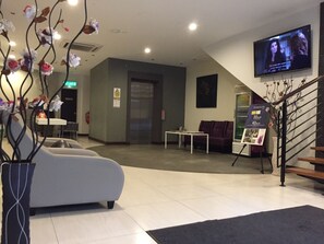 Un hall d’entrée moderne avec un canapé, une petite table, un téléviseur et un escalier.