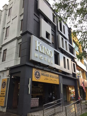 Un hôtel appelé KINO HOTEL, avec une enseigne indiquant « MUAR STATION » en dessous.