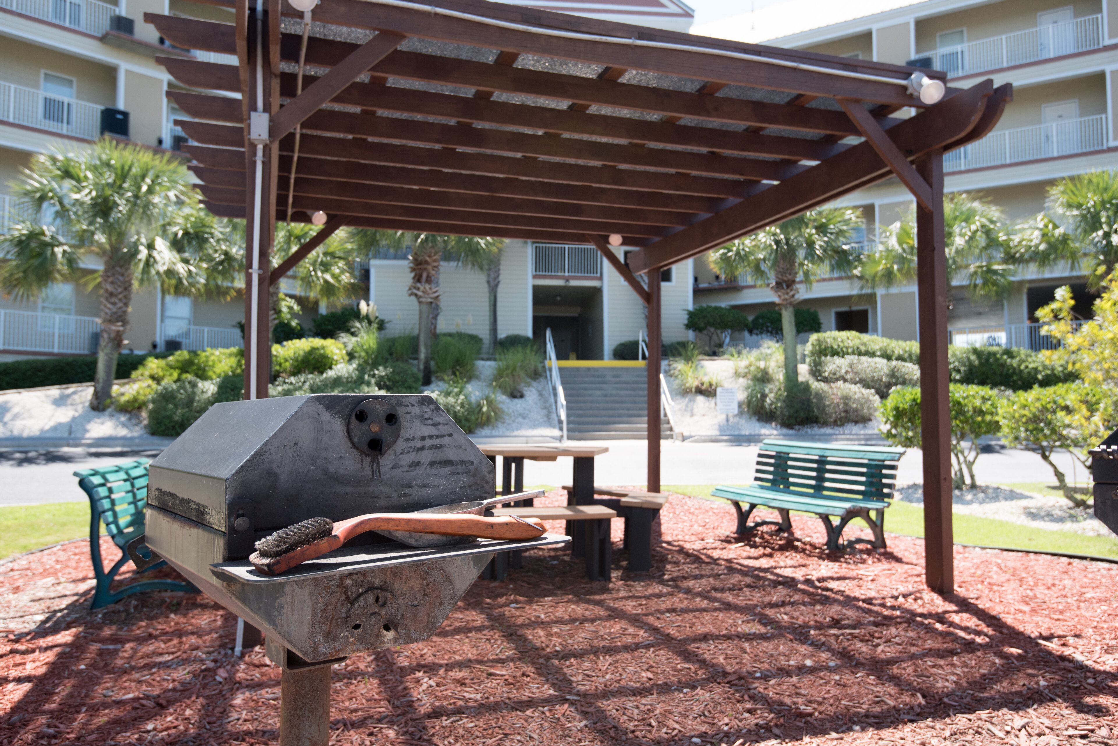 An outdoor barbecue area with a grill, seating, and a covered pavilion.